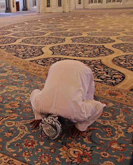 Muslim man kneels in prayer inside a Mosque